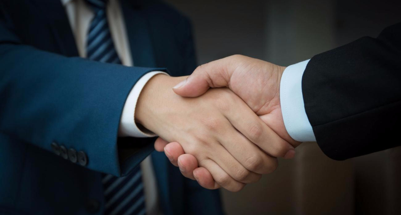Two professionals shaking hands, representing a new business association.