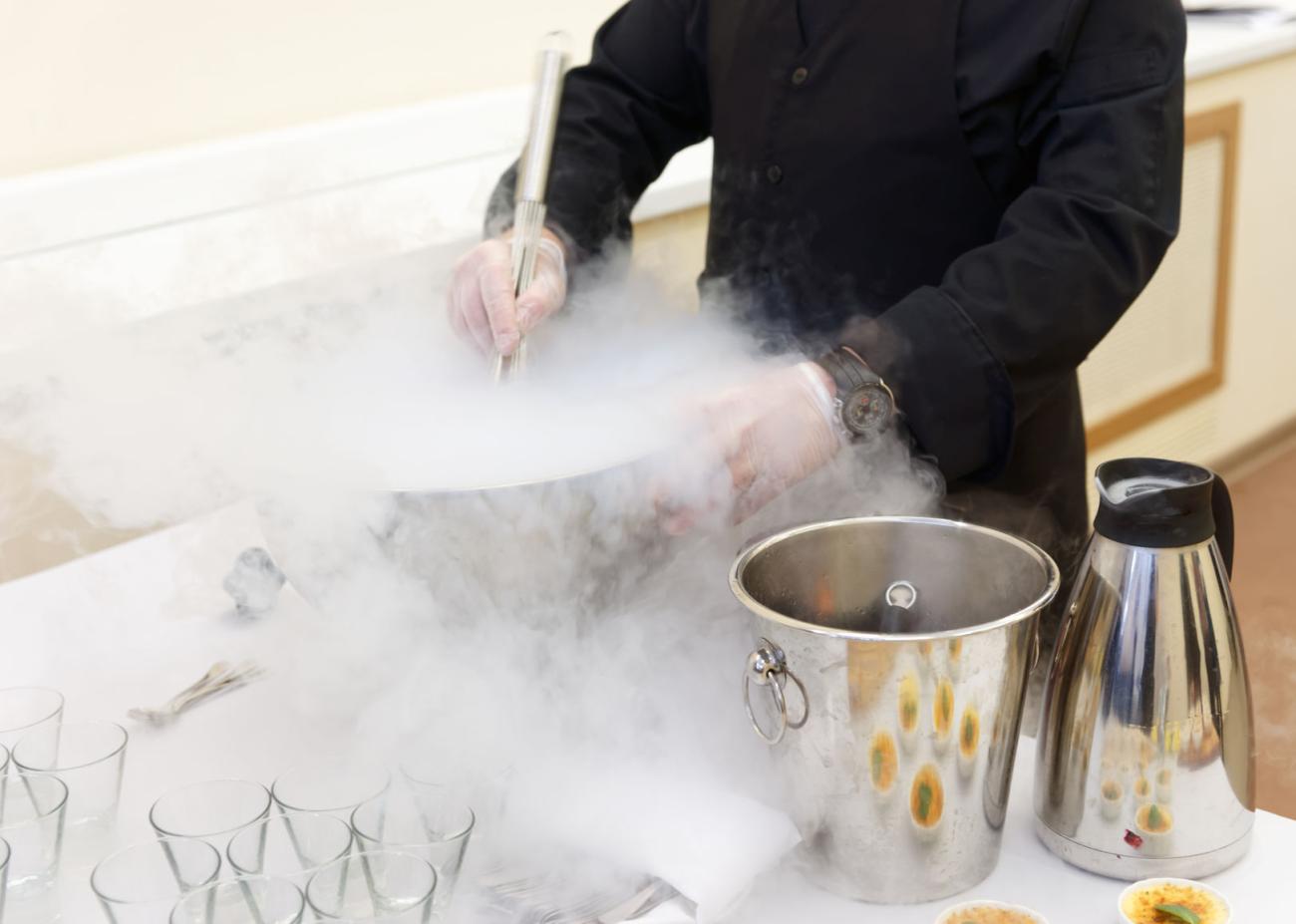 A technician carefully dispensing liquid nitrogen, white cryogenic vapour rising from the vessel.